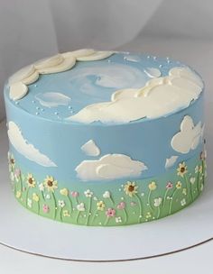 a blue cake with clouds and flowers on it