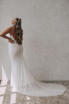 a woman in a white wedding dress is looking down at the floor and back of her gown