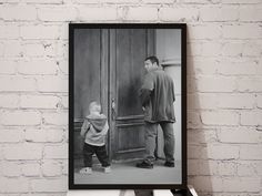 a black and white photo of a man standing next to a child in front of a door