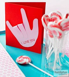 lollipops in a glass vase on a blue tray with a red card that says i love you