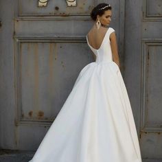 a woman in a white wedding dress standing next to an old metal door with the word love written on it