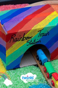 there is a colorful train coming out of the rainbow train station box on this cake