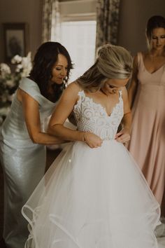 bridesmaids helping the bride put on her wedding dress