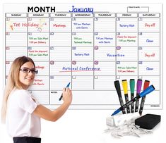 a woman writing on a calendar with markers and pencils in front of the calendar