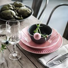 the table is set with pink plates and silverware