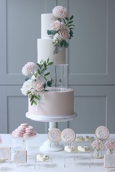 a three tiered wedding cake with flowers on top and cookies in the bottom for decoration