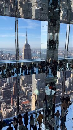 many people are standing in front of the glass wall looking out at the cityscape