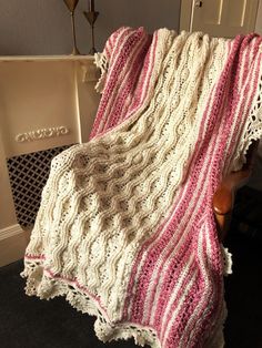 a white and pink blanket sitting on top of a chair