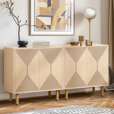 a wooden sideboard with geometric design in a living room area next to a painting on the wall