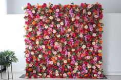 an artificial flower wall is shown in front of a potted plant