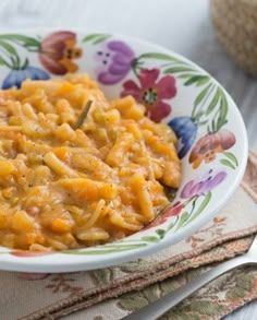 a bowl filled with macaroni and cheese sitting on top of a table next to a fork