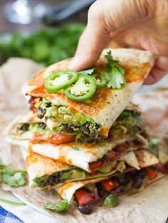 a hand holding a tortilla filled with veggies