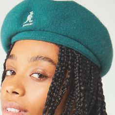 a woman with braids wearing a green hat