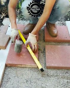 a man kneeling down on some bricks with a ruler in front of him and measuring the area