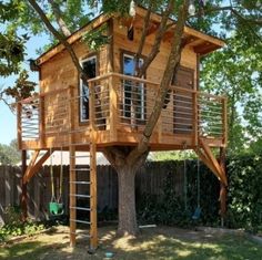 a tree house built into the side of a fenced in yard with a swing set