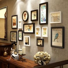 there are many framed pictures on the wall with flowers and candles in front of them