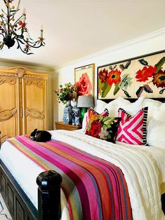 a bed with colorful blankets and pillows in a bedroom next to a chandelier