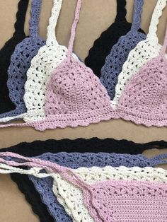 two crocheted bras with pink and white lace on the bottom, one black and one blue