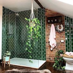 a bathroom with green tiles on the walls and wood flooring, including a shower