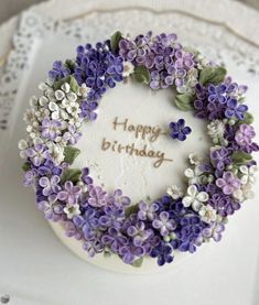 a birthday cake decorated with purple and white flowers