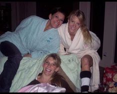 three women wrapped in blankets posing for the camera