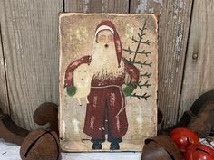 an old fashioned christmas card with santa holding a teddy bear and other ornaments on a wooden surface