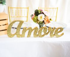 the table is set with gold glitter name signs and flowers in vases on it