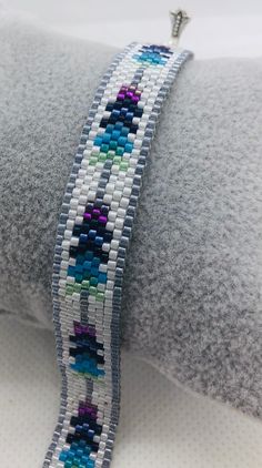 a close up of a beaded bracelet on top of a white pillow with a silver clasp