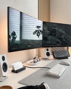 two computer monitors sitting next to each other on top of a white desk in front of a window