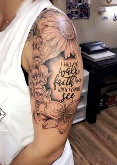 a woman with a sunflower and bible verse tattoo on her arm, in a living room