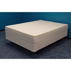 a white mattress sitting on top of a blue carpeted floor next to a wall