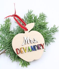 an apple ornament with the words mrs devandry hanging from it's side