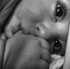 a black and white photo of a baby's face with her hands on her head