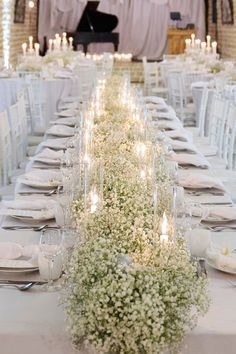 a long table is set with white flowers and candles for an elegant dinner party or reception