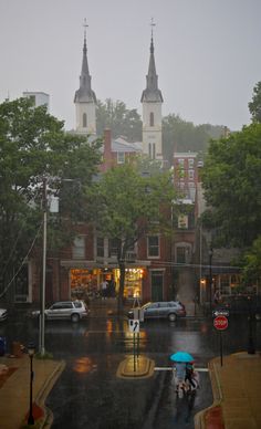 two people with umbrellas crossing the street in the rain