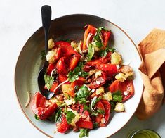 a white bowl filled with lots of food next to a napkin and glass on top of a table