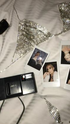 an old camera and several polaroid photos on a bed with silver sequins