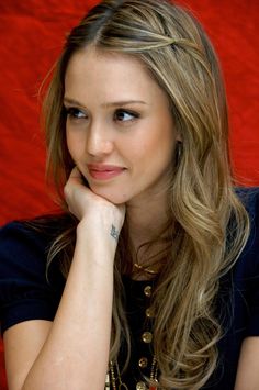 a beautiful young woman sitting down with her hand on her chin