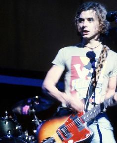 a young man playing an electric guitar on stage