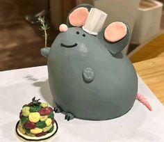 there is a cake shaped like a rat and a small flower on the table next to it