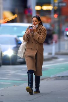 a woman walking down the street while talking on her cell phone and holding a bag