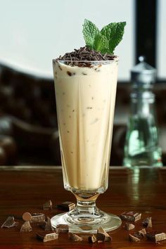 a drink with chocolate and mint garnish in a tall glass on a wooden table