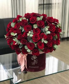 a bouquet of red roses sitting on top of a glass table