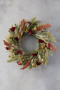 a wreath made out of dried flowers on a gray background with space for text or image