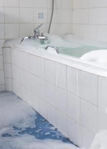 a bathtub with foam on the floor and water running down it's side