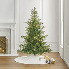 a small christmas tree is sitting on the floor in front of a fireplace with presents under it