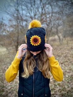 a woman wearing a knitted hat with a sunflower on the front and side