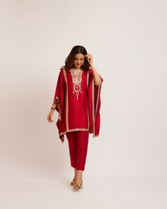 a woman wearing a red outfit with gold trimmings and an embroidered design on the front