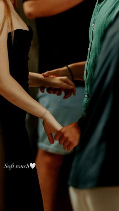 two people holding hands while standing next to each other in front of another person wearing a green shirt