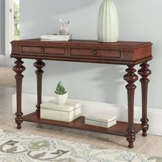 a wooden table with two drawers and a vase on top, in a living room